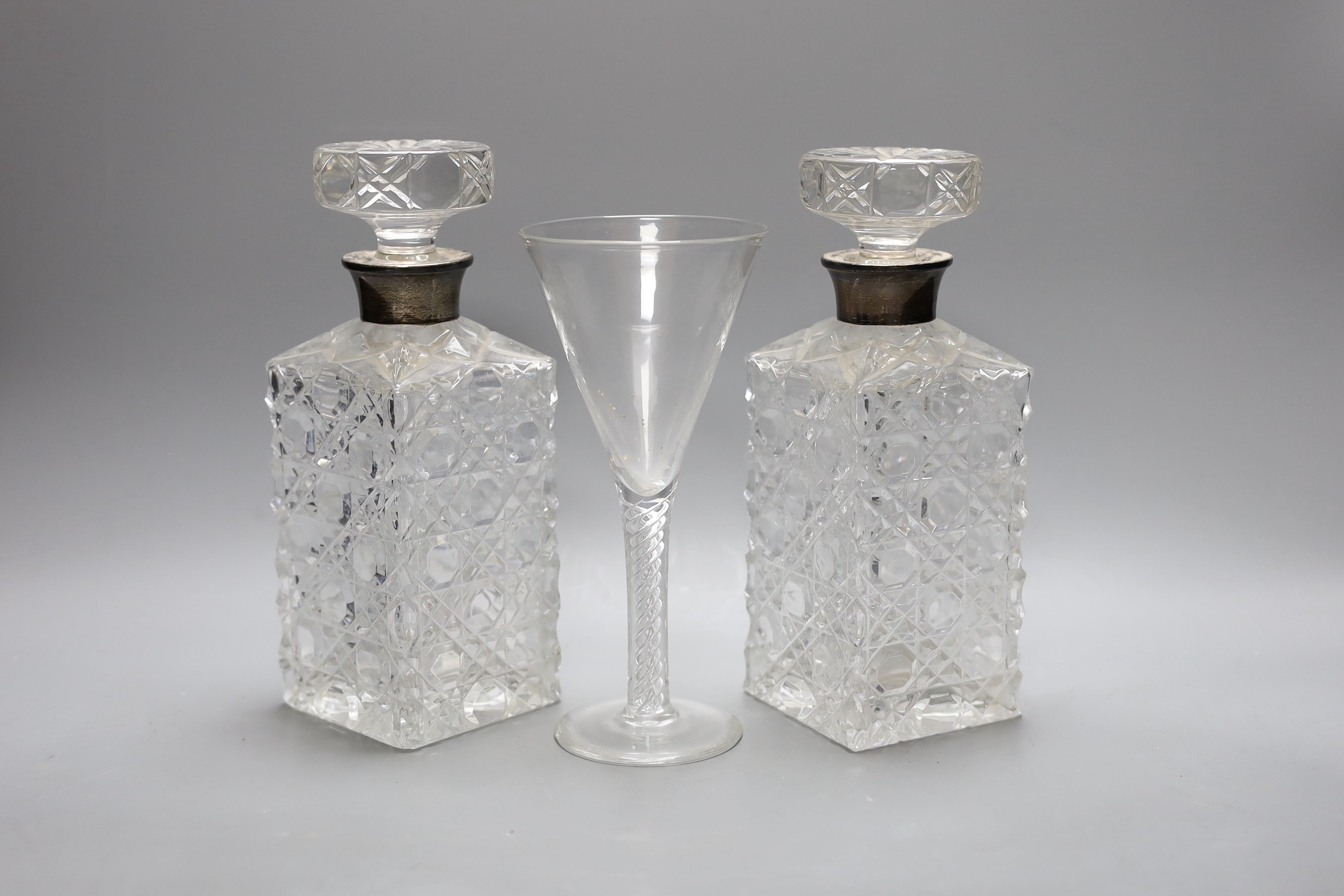 A pair of silver mounted cut glass decanters and stoppers and an air twist stemmed goblet, decanters 24 cms high